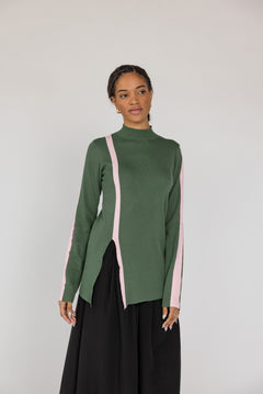 Woman wearing a green long-sleeve top with pink accents on a white background