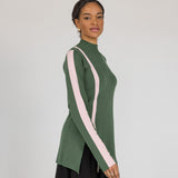 Woman wearing a green mock neck with pink stripes on a plain background