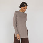 Woman wearing a brown long-sleeve top and wide-leg pants on a white background