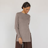 Woman wearing a brown long-sleeve top and wide-leg pants on a white background