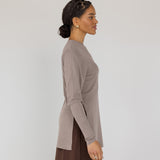 Woman wearing a beige long-sleeve top and brown skirt on a white background