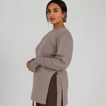 Woman wearing a beige long-sleeve top with a high-low hem on a white background