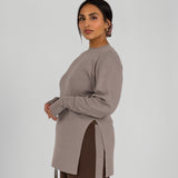Woman wearing a beige long-sleeve top with a high-low hem on a white background