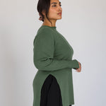 Woman wearing a green long-sleeve top against a white background
