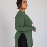 Woman wearing a green long-sleeve top against a white background