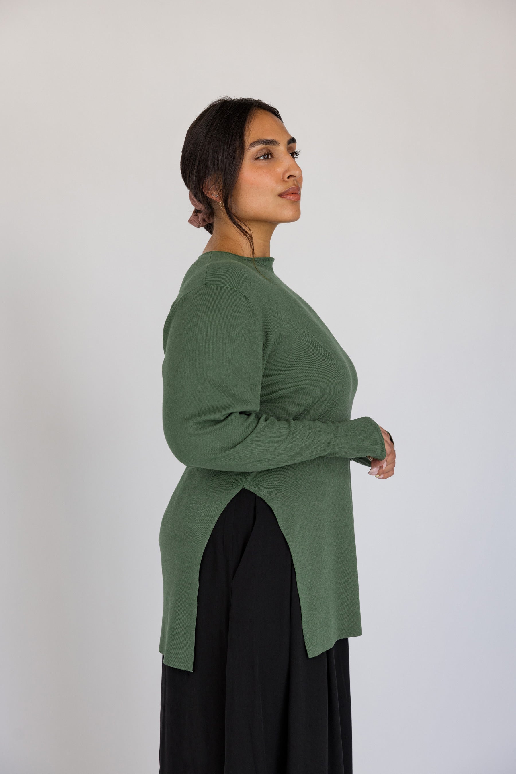 Woman wearing a green long-sleeve top against a white background