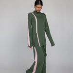 Person wearing a green outfit with pink accents on a gray background