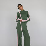 Woman wearing a green outfit with pink stripes on a white gray background