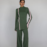 Woman wearing a green outfit with pink accents on a white gray background