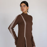 Woman wearing a brown outfit with truffle stripes on a plain background
