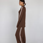 Woman wearing a brown outfit with truffle stripes on a white background