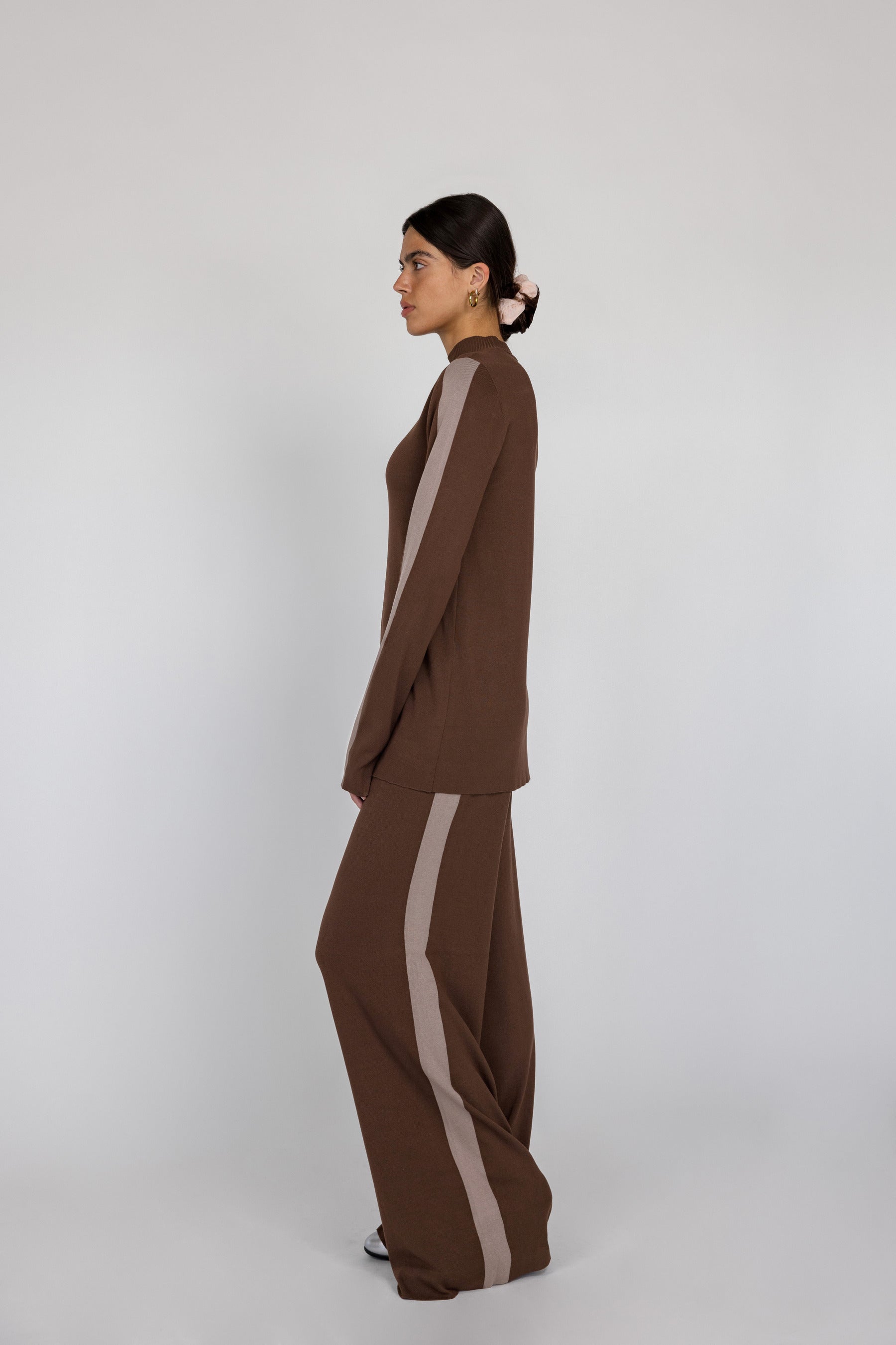 Woman wearing a brown outfit with truffle stripes on a white background