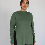 Woman wearing a green long-sleeve top against a plain background