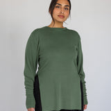 Woman wearing a green long-sleeve top against a plain background