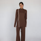 Woman wearing a brown outfit with truffle stripe against a white background