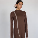 Woman wearing a brown outfit with a high neckline and long sleeves on a white background