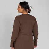 Woman wearing a brown outfit against a plain background