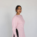Woman wearing a light pink sweater against a plain background