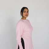 Woman wearing a light pink sweater against a plain background