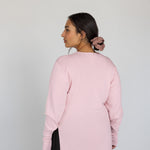 Person wearing a light pink knit top against a white background