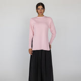 Person wearing a pink knit top and black pants on a white background
