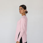 Woman wearing a pink sweater and black pants on a white background