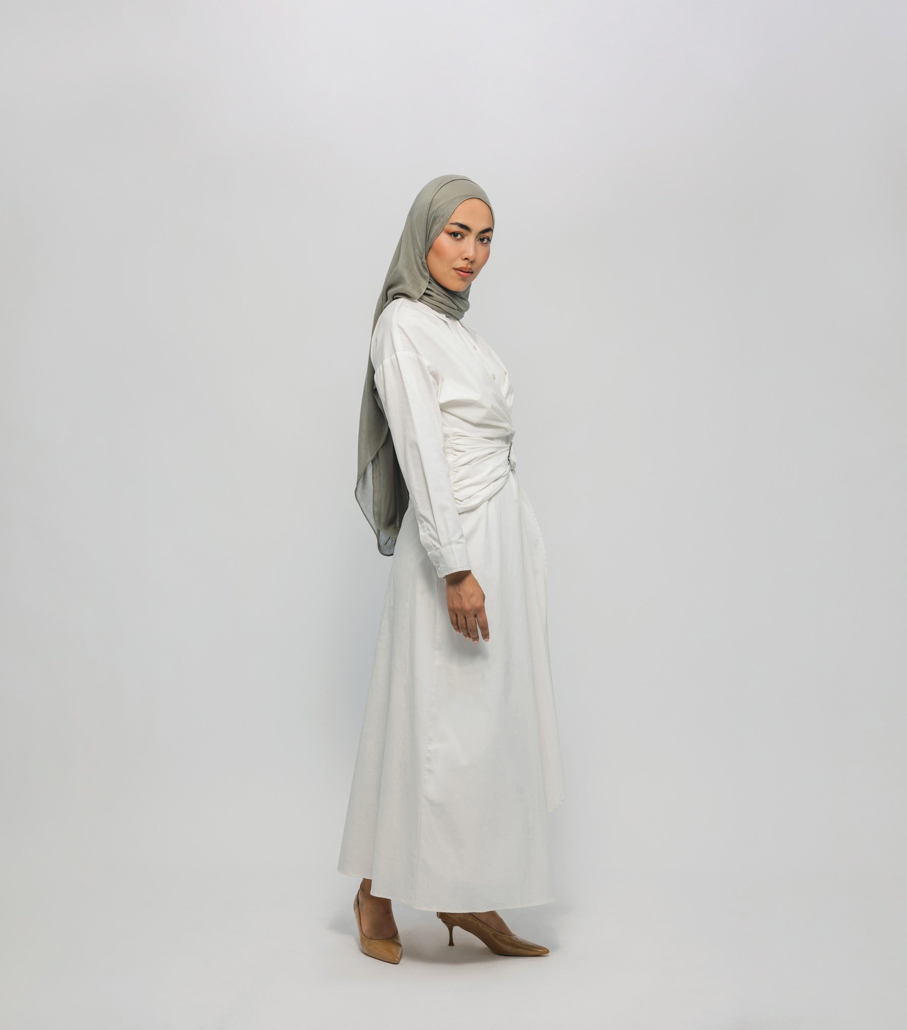 Woman wearing a white dress and gray hijab on a white background