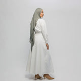 Woman wearing a white outfit with a gray hijab on a plain background