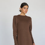 Woman wearing a brown long-sleeve top against a white background