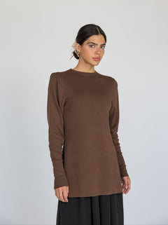 Woman wearing a brown long-sleeve top against a white background