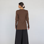 Person wearing a brown long-sleeve top and black wide-leg pants on a white background