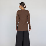 Person wearing a brown long-sleeve top and black wide-leg pants on a white background