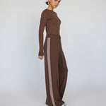 Woman wearing a brown outfit with wide-leg pants on a white background