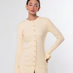A woman modeling a pale cream long-sleeve knit cardigan with a button front, photographed against a clean light gray studio background.