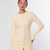 A woman modeling a pale cream long-sleeve knit cardigan with a button front, photographed against a clean light gray studio background.
