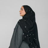Woman wearing a black hijab with star beaded patterns on a gray background