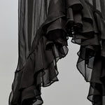 Black sheer ruffled fabric, likely a curtain or scarf, hanging against a plain light gray background.