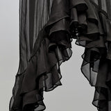 Black sheer ruffled fabric, likely a curtain or scarf, hanging against a plain light gray background.