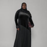 Woman wearing a black abaya and hijab on a gray background