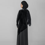 Woman wearing a black abaya and hijab on a gray background