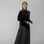 Woman wearing a black abaya with a hijab on a gray background