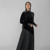 Woman wearing a black abaya with a hijab on a gray background