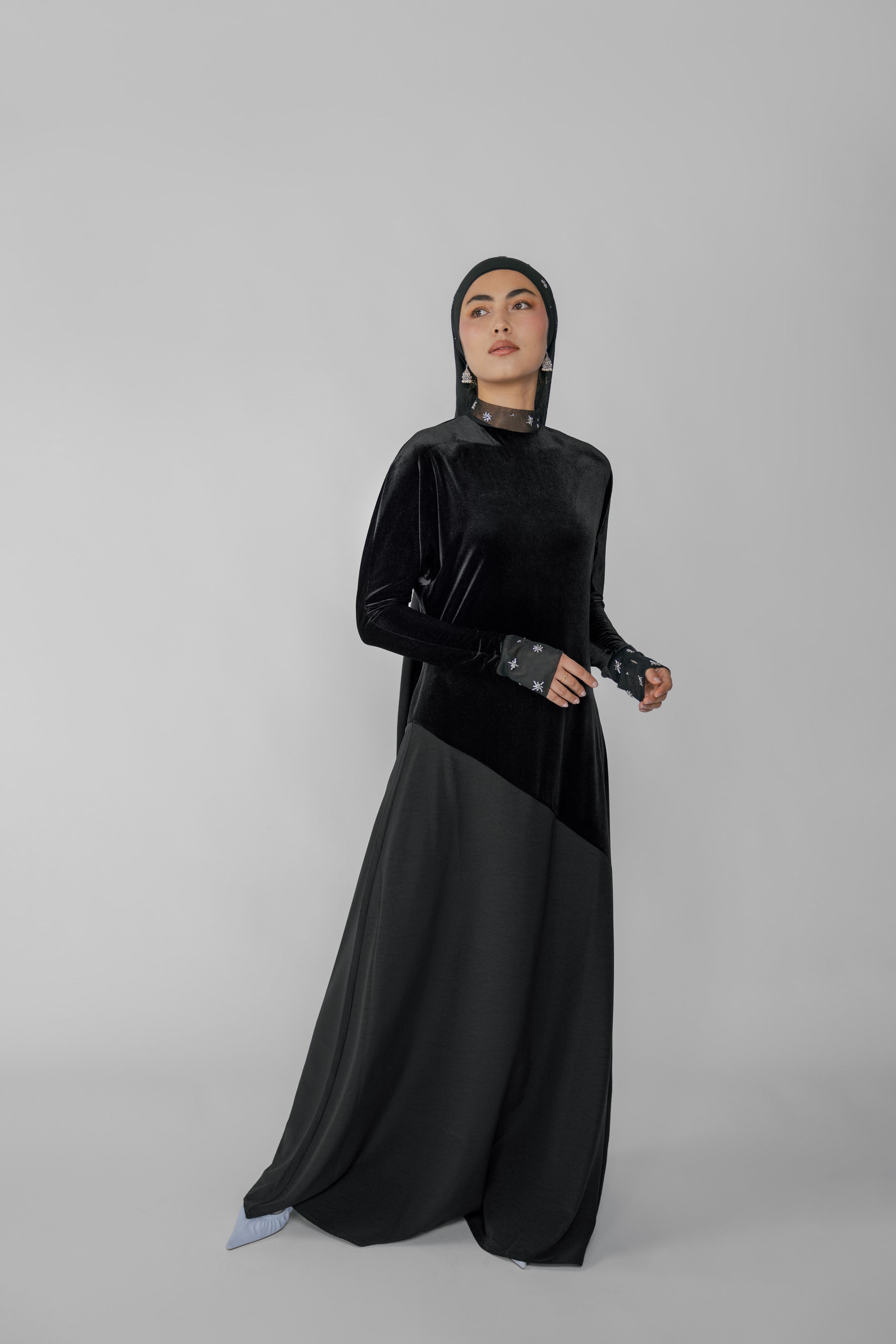Woman wearing a black abaya with a hijab on a gray background