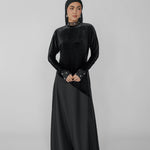 Woman wearing a black dress with a hijab on a gray background
