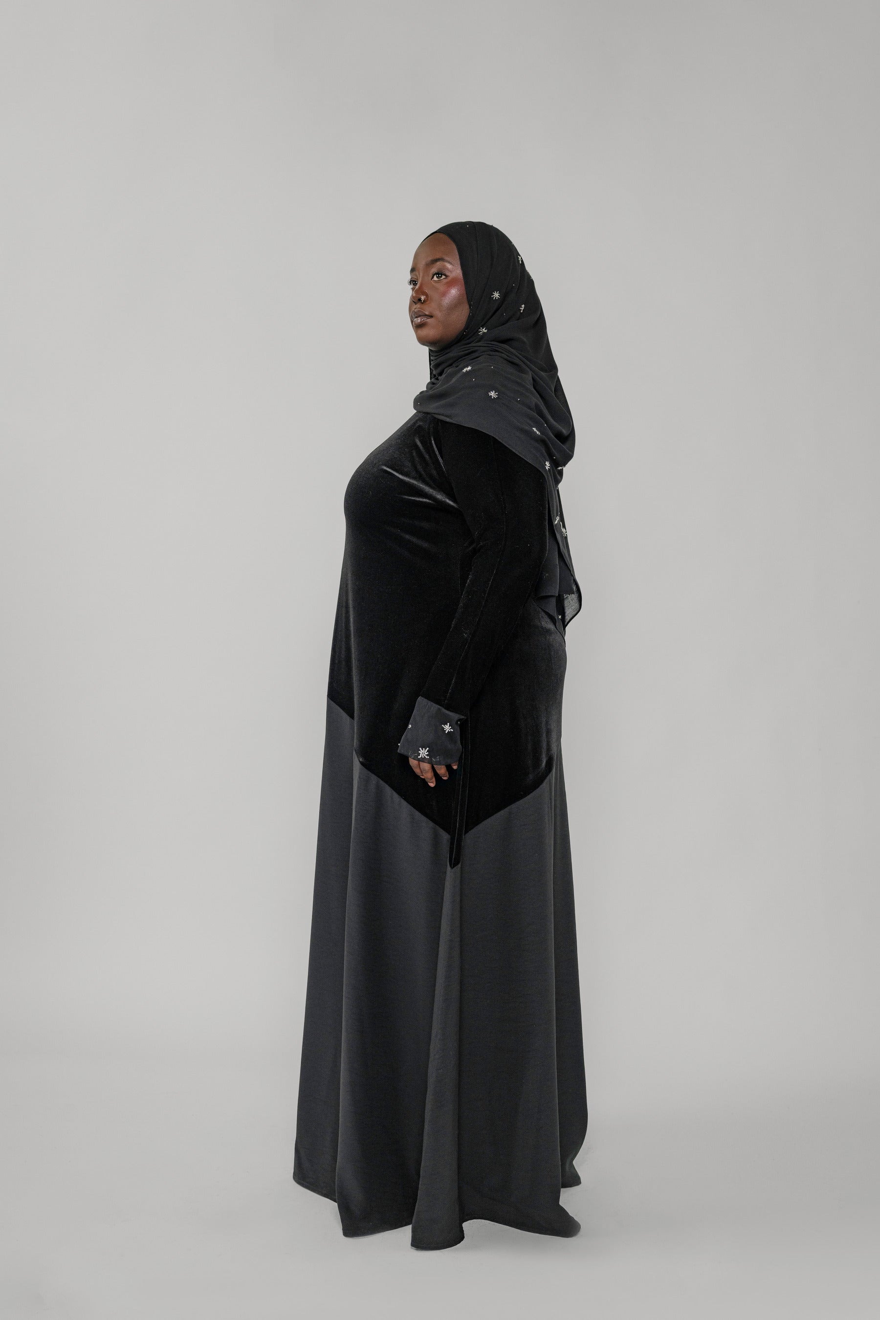 Woman wearing a black dress with a hood on a white background