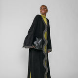 Woman wearing a black abaya with green dress on a white background