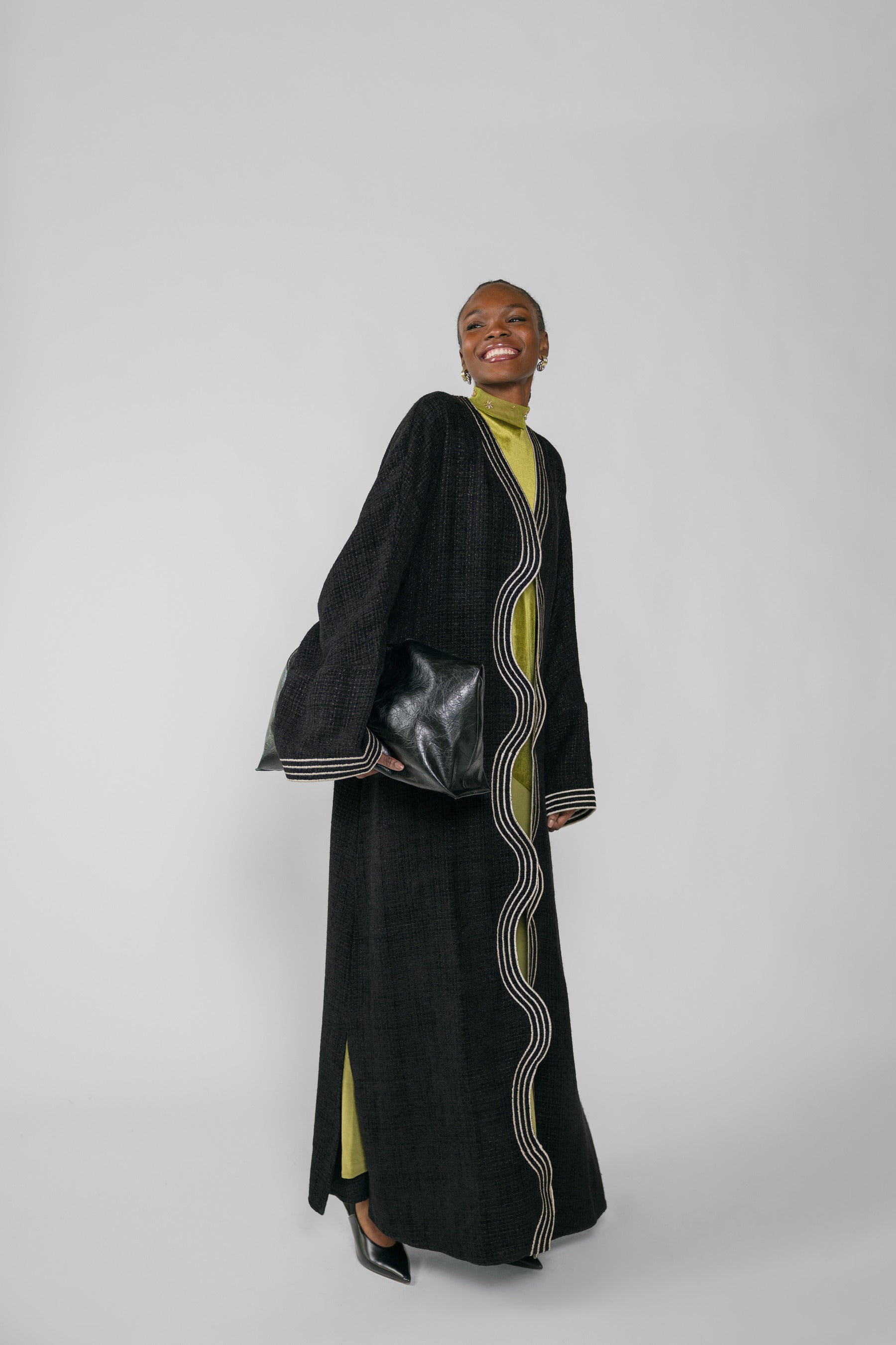 Woman wearing a black abaya with green dress on a white background