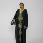 Woman wearing a long black abaya with green dress on a white background