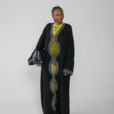 Woman wearing a long black abaya with green dress on a white background