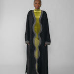 Woman wearing a black abaya and green dress with a white background